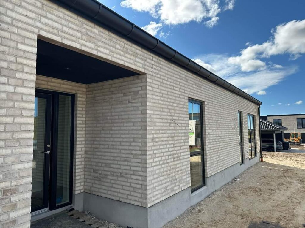 Nybygget murstenshus under klar blå himmel